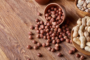 A composition from different varieties of nuts in a wooden bowls on rustic background, close-up, shallow depth of field