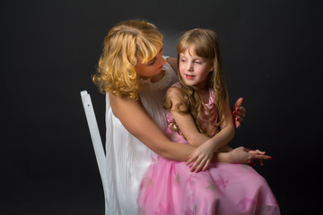 Mother gently hugs her daughter. The daughter of a pink dress.
