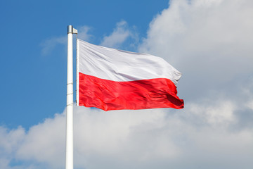 Fototapeta na wymiar Polska flaga narodowa powiewająca na tle niebieskiego nieba