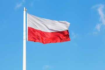 Polska flaga narodowa powiewająca na tle niebieskiego nieba