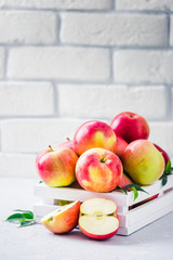 Delicious red apples in white wooden box on light background. Selective focus, space for text.