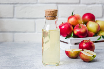 Fermented apple cider and fresh red apples in white wooden box on light background. Selective focus, space for text.