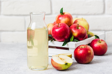 Fermented apple cider and fresh red apples in white wooden box on light background. Selective focus, space for text.