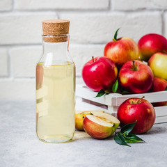 Fermented apple cider and fresh red apples in white wooden box on light background. Selective focus, space for text.