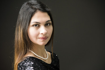 Closeup portrait of an attractive young woman in black dress. Outdoor portrait of a beautiful woman, black wall in background.