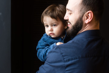 Father and son in hugs at black background