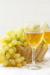 Glass of wine and grapes in the basket on a wooden table.