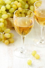 Glass of wine and grapes in the basket on a wooden table.