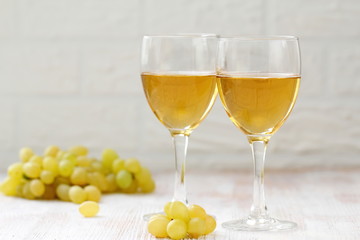 Glass of wine and grapes in the basket on a wooden table.