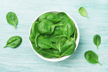 Fresh spinach leaves in bowl on table top view. Organic food.