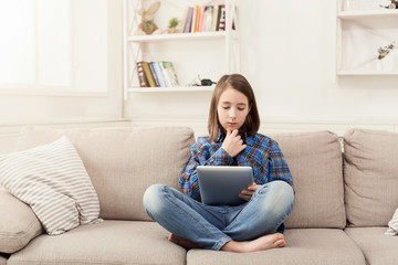 Pensive girl with digital tablet at home