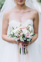 Obraz na płótnie Canvas A bride in a white dress is holding a beautiful wedding bouquet.