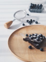 close up hot brownie with fresh blueberry on wooden plate.