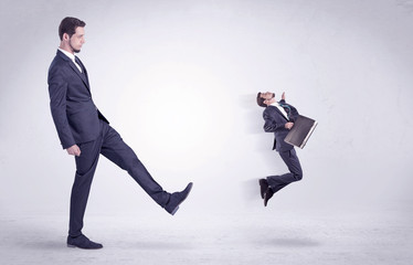 Big man in suit kicking out little himself out with simple white wallpaper
