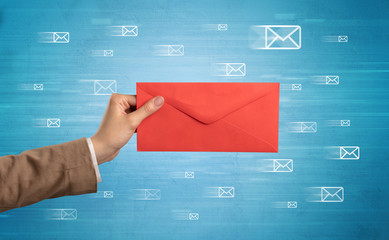 Female hand holding coloured and white envelope with blue background and message symbols around
