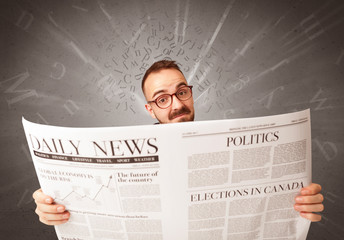 Young smart businessman reading daily newspaper with alphabet letters above his head