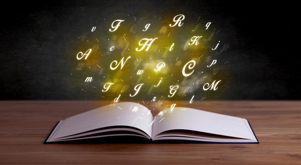 Glowing yellow alphabet letters coming out of an open book 