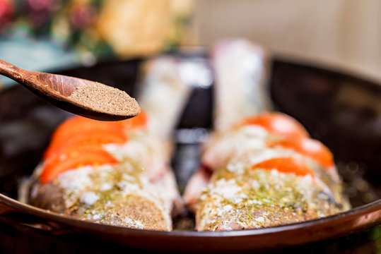 Adding Spices To Raw Zander Fish On Frying Pan