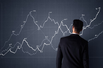 Young businessman in black suit standing in front of a progress chart