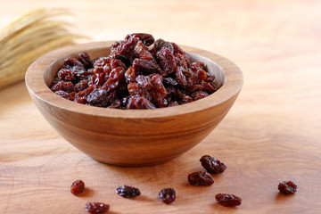 Raisin in bowl on wooden background.