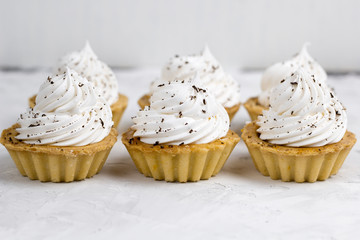 three cupcake with cream decorated with chocolate chips concrete background