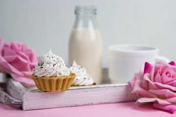 cupcake on a wooden tray with rose flowers, milk bottle and coffee cup, romantic breakfast on a vintage wooden tray