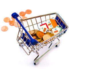 Miniature house with golden stack coins on mini shopping cart isolated on white background using as business, property and financial concept - Vintage filter
