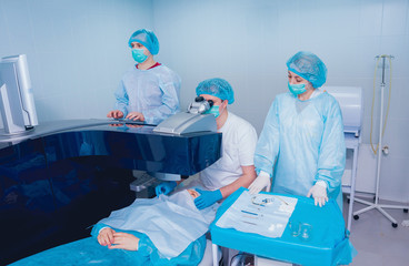 Laser vision correction. A patient and team of surgeons in the operating room during ophthalmic...