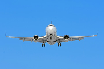 Airplane ready for landing flying in the blue sky with landing gear and flaps.