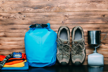 Trekking shoes, camping gas bottle and equipment for outdoor activities on a wooden background....