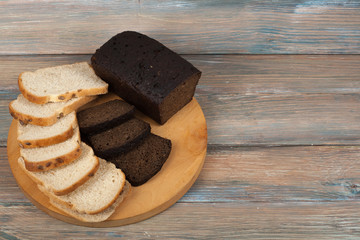 Many mixed breads and rolls of baked bread on wooden table background.