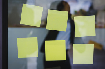blank yellow sticky note or post note stuck on glass wall.