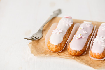 Traditional french eclairs on white table with pink flower. Copyspace