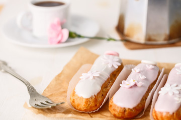 Traditional french eclairs on white table with pink flower. Copyspace