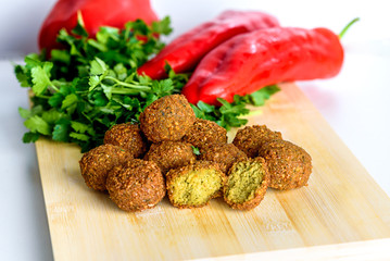 Falafel balls,sweet red pepper and green fresh parsley on a wooden background.Falafel is a traditional Middle Eastern food.