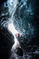 Man wear red coated hiking the ice wall to get to the top / Adventure concept / outdoor activity / Sport concept