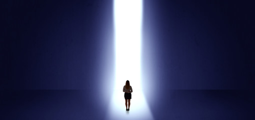 Woman standing and seeing the light at the end of a big wall
