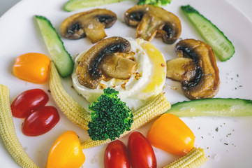 Healthy brunch idea on a white plate scrambled eggs with vegetables corn mushrooms cucumbers.