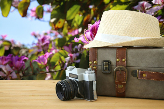 traveler vintage luggage, camera and fedora hat over wooden table infront of . holiday and vacation concept.