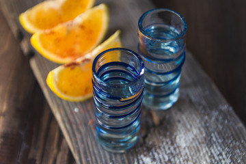 Traditional mexican mezcal shots served with orange on a wooden background