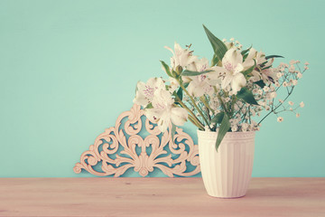 summer bouquet of white flowers in the vase over wooden table and mint background.