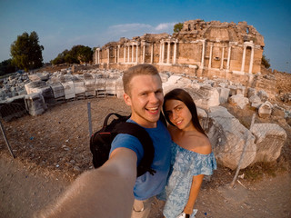 Couple of tourists making selfie on camera in background of Greek ruins in Turkey, Greece. Concept travel, lifestyle