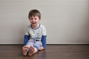  The boy is upset, crying and protesting. Sits in the room on the floor.