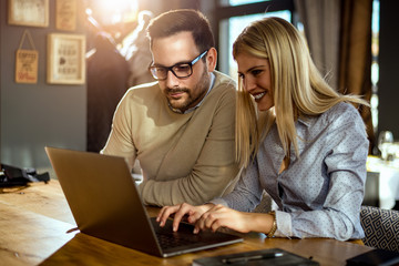 Two young people sitting at a cafe, using a laptop