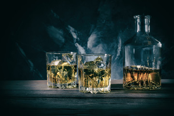 Decanter and two glasses of whiskey on marble background