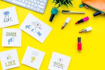 Beauty blogging concept. Work desk with keyboard, cosmetics and social media icons on yellow desk top view
