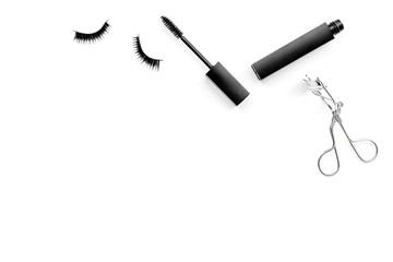 Cosmetics and tools for voluminous lashes. Mascara, false eyelashes, eyelash curler on white background top view space for text