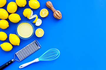 Cook lemon curd. Sweet cream in bowl, fruits, kitchen utensils on blue background top view copy space