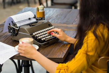 Cropped shot of a writer's hands typing on retro typewriter