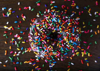 overhead studio shot of a donut with sprinkles on a wooden background unhealthy food concept